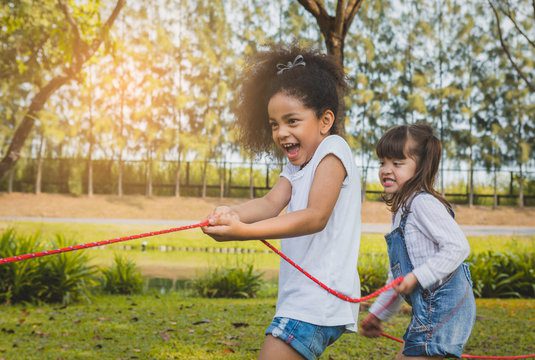 Happy kids playing rope tug of war in park