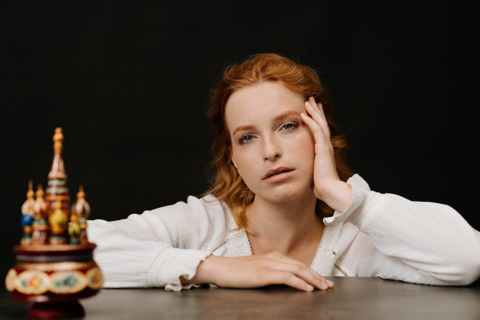 Woman in White Long Sleeve Shirt Leaning on Brown Wooden Table